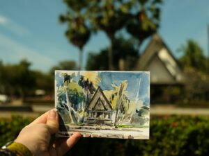 a person holding up a piece of paper with a painting on it