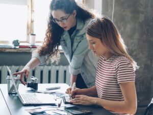 Two women work on a laptop together.